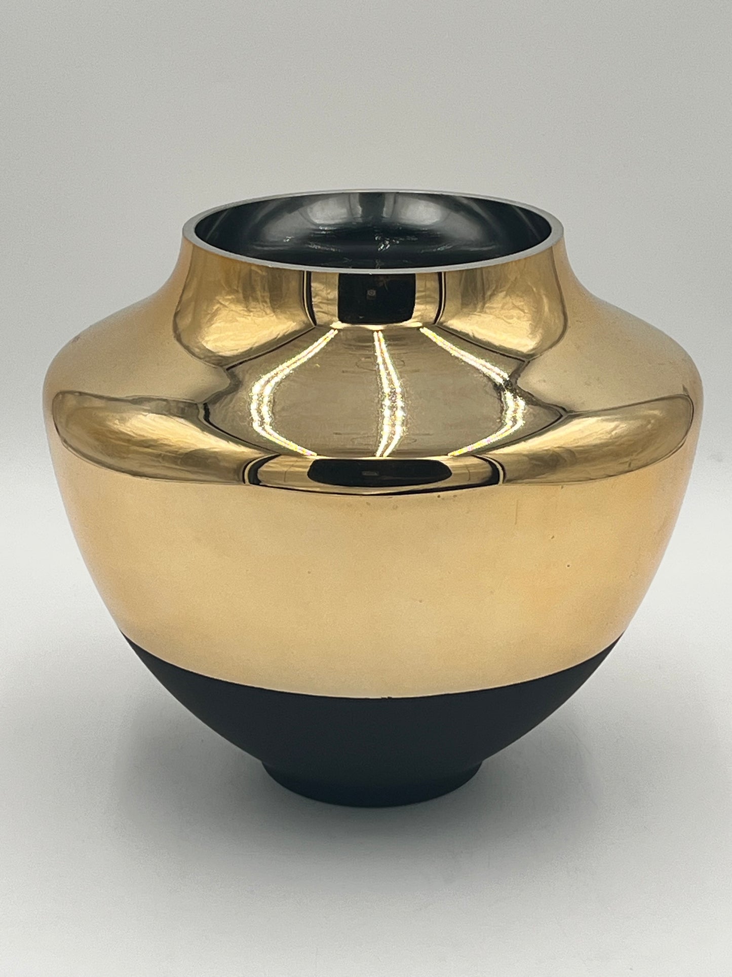The Altura 9 x 5 Op vase by Floral Supplies Point features a shiny gold and black ceramic design with a wide body, narrow neck, and round opening, reflecting light against a plain white background for an elegant, architectural look.
