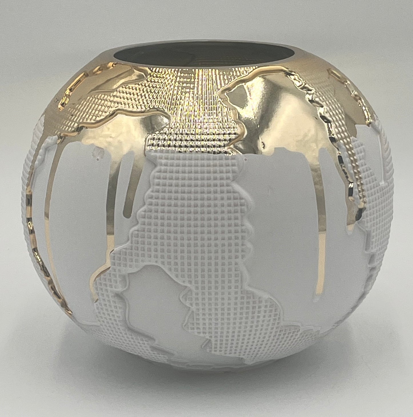 The Auralis Terra 6.5x3.5 Op by Floral Supplies Point is a round white vase featuring raised continents and shimmering gold accents, creating a stylish sculptural tribute to the world’s beauty.