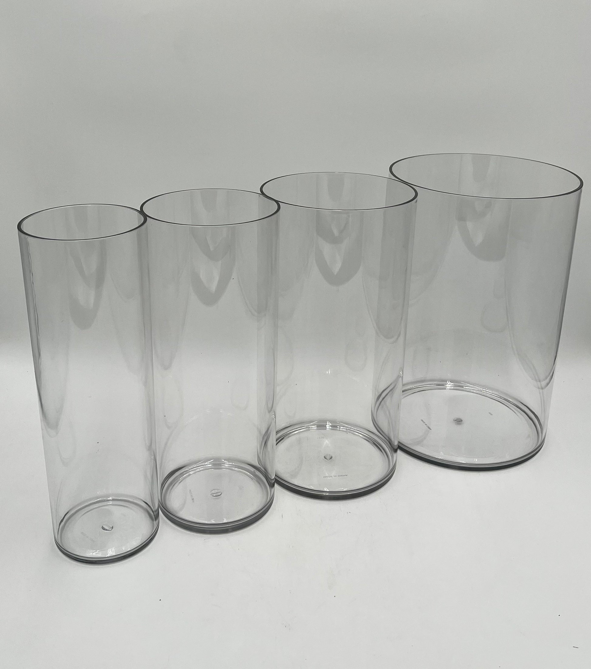 Clear plastic cylinder vases in four sizes for floral design, candles, or decor use. Lightweight and modern. Sold individually by floralsuppliespoint1.com.