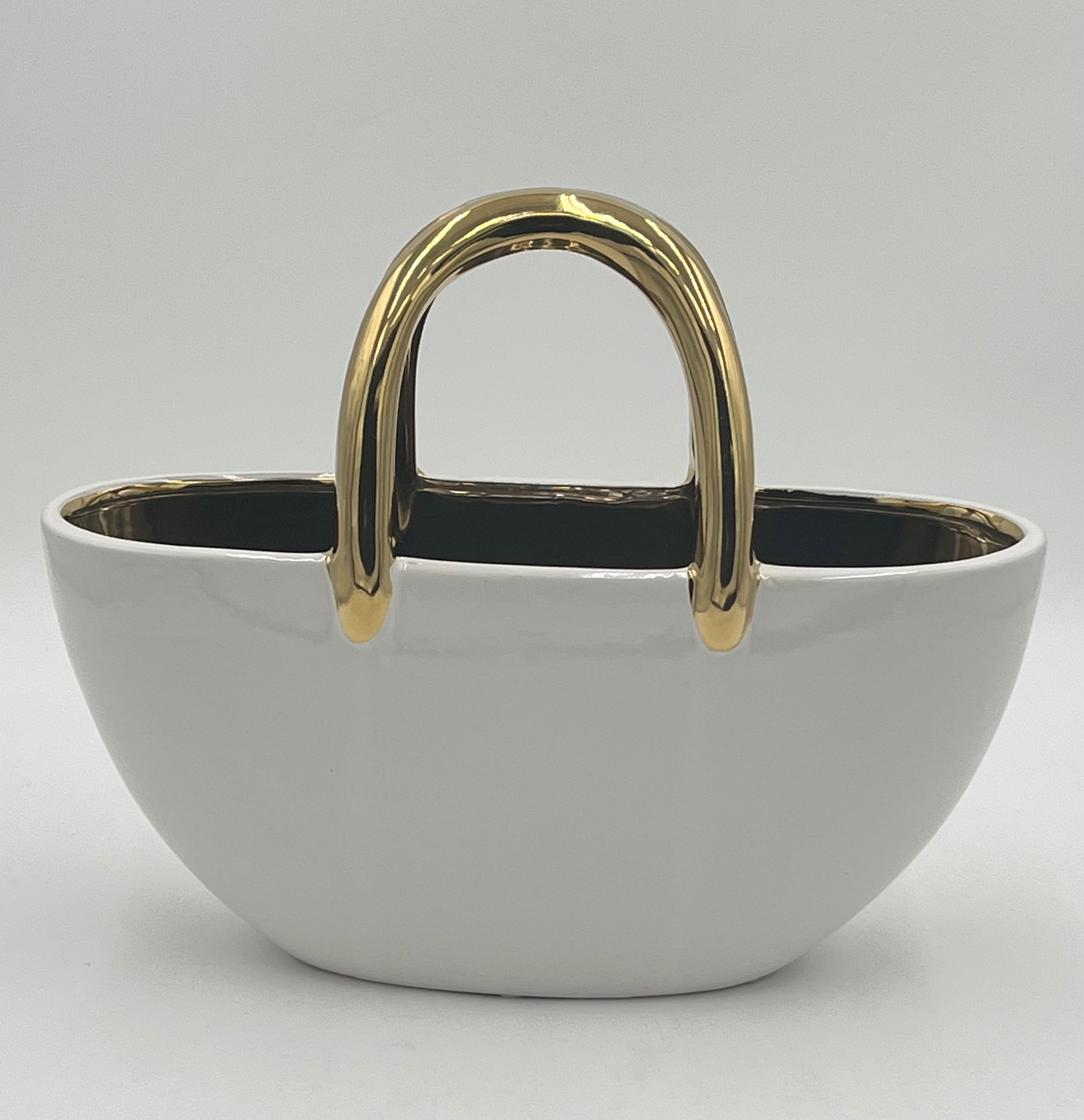 The Arcora 10 x 11.5 Op by floralsuppliespoint1.com is a glossy white ceramic basket-shaped container with a shiny gold handle and gold rim accents, inspired by modern handbags, shown on a plain white background.