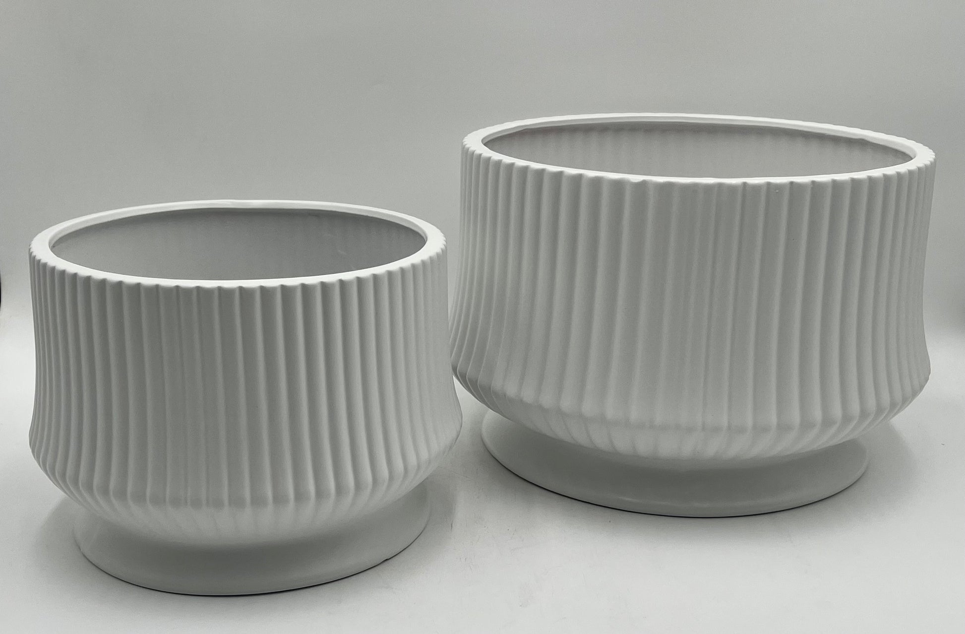 Cove Ridge Set ceramic vases in white with ribbed design and pedestal base, sizes 8"x10.5 Op and 6.5"x8 Op, total weight 11.50 lbs, available at floralsuppliespoint1.com.