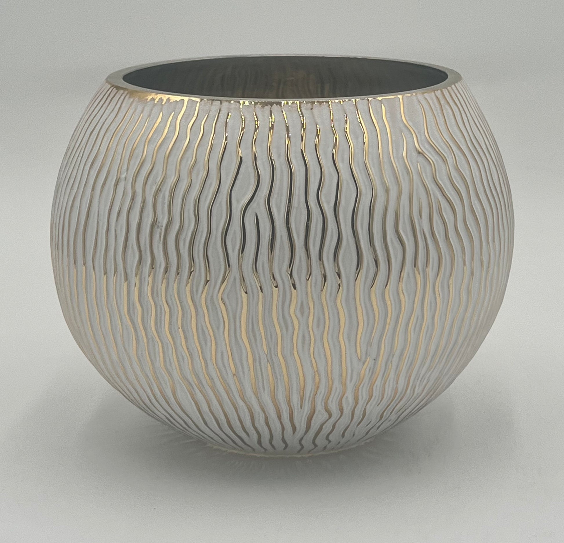 The Lunara Orb 6x5 Op by Floral Supplies Point is a round white ceramic vase with a glossy finish and wavy gold vertical lines, featuring a wide opening and smooth, modern design—perfect as a sculptural décor accent.