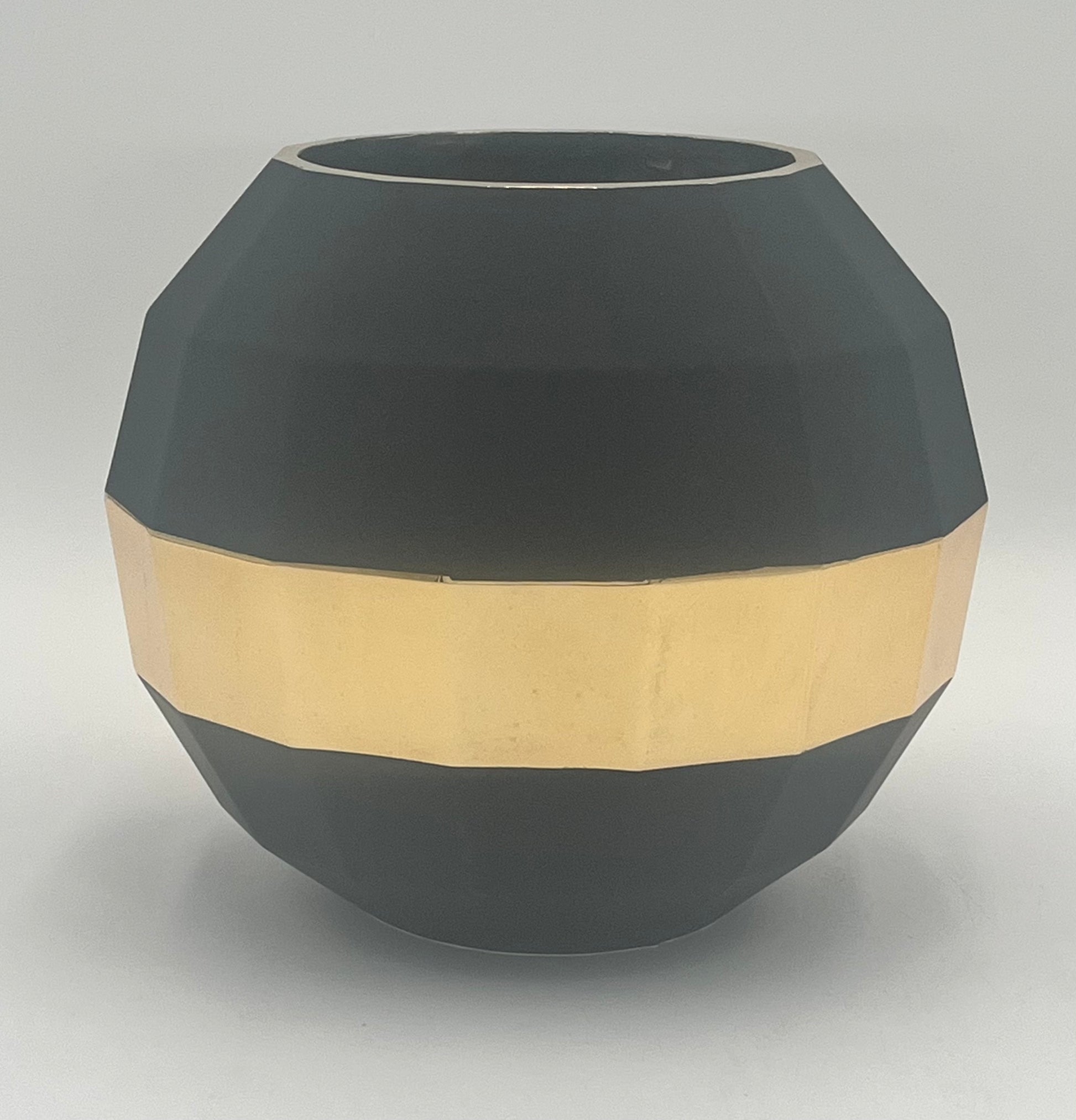 The Stratos Core 7x4 Op vase by Floral Supplies Point features a matte black, faceted round design with a wide gold band, creating a sculptural centerpiece that radiates grounded luxury against a plain white background.