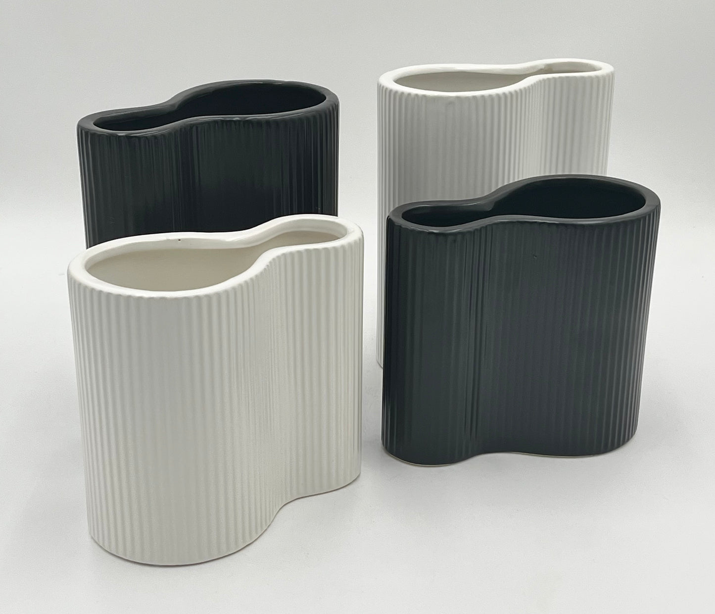 Twin Current vases in matte black and white with ribbed texture, sold by floralsuppliespoint1.com. Includes medium (8"x6") and small (6"x6") ceramic vases for modern floral designs.